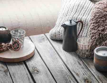 mesa tabla madera cafetera vela hojas secas lana inverno